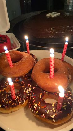 three donuts with candles are on a plate