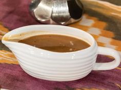 a white bowl filled with liquid sitting on top of a table next to a coffee pot