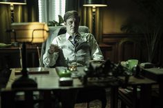 a man sitting at a table in front of a desk with a lamp on it