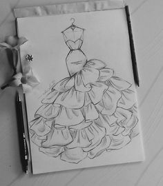 a drawing of a dress on paper next to flowers