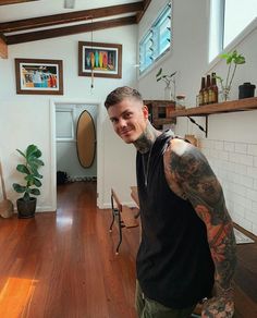 a man with tattoos standing in a room