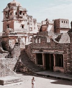 a woman standing in front of an old building with steps leading up to the top