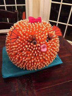 an orange and pink sculpture sitting on top of a blue cloth covered table next to a window