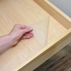 a person's hand on top of a wooden table with a piece of paper