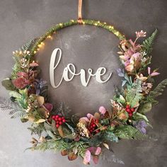 a wreath with the word love written on it and surrounded by greenery, berries and leaves