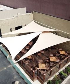 an aerial view of a building with several tables and chairs under a white awning