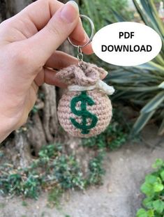 a hand holding a crocheted keychain with a dollar sign on it