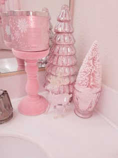 there are three pink christmas trees on the bathroom counter next to the sink and mirror