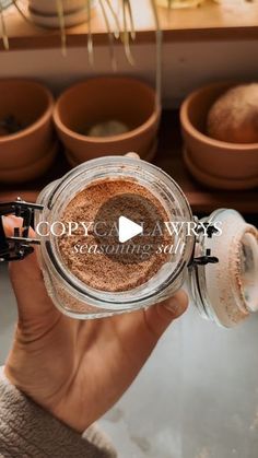 a person holding up a jar filled with brown powder