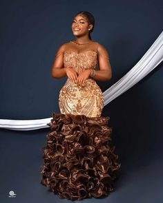 an african woman in a gold and brown dress with her hands on her hips, posing for