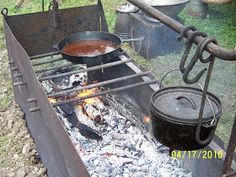 an outdoor grill with pots and pans cooking on it's burners in the grass