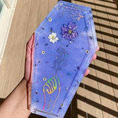 a hand holding a purple case with flowers on it