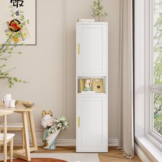 a tall white cabinet sitting in the corner of a living room next to a window