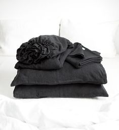 black linens are stacked on top of each other on a white bedding set