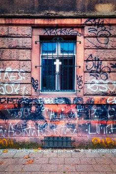 an old building with graffiti all over it and a cross on the window sill