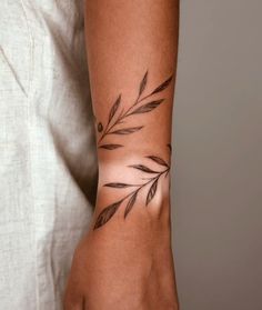 a woman's arm with a tattoo on it that has leaves and dots in the middle