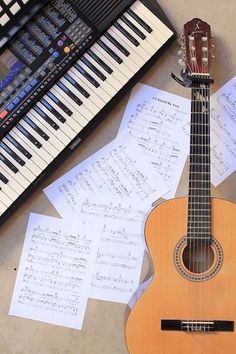 an ukulele and sheet music sit on the floor next to a piano keyboard