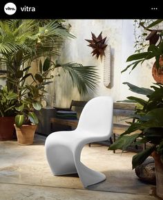 a white chair sitting on top of a floor next to potted plants