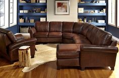 a living room filled with lots of furniture and bookshelves next to a window