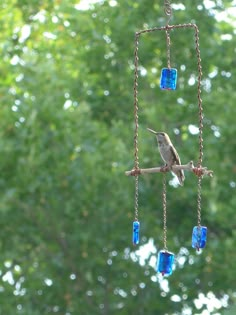 a bird is perched on a branch with blue glass beads hanging from it