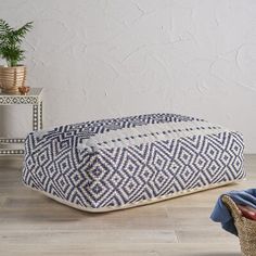 a blue and white floor pillow sitting on top of a wooden floor next to a basket