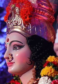 a close up of a statue with flowers on it's head and an ornate crown