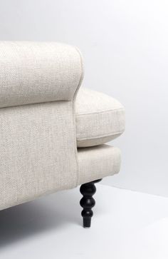 an upholstered white couch with black legs and foot rests against a plain background