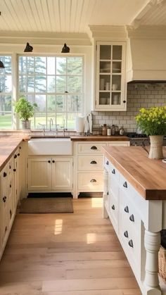 a kitchen with white cabinets and wooden counter tops in front of a large open window