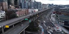 an aerial view of a city street with cars driving on the road and tall buildings in the background