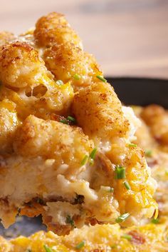 a piece of chicken and cheese casserole being lifted from a skillet