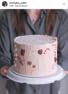 a woman holding a cake decorated with flowers on it's side and in front of her