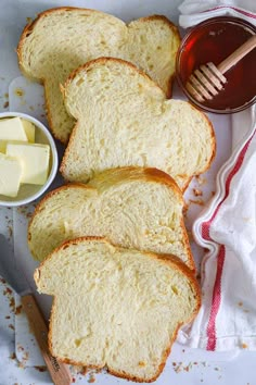 slices of white bread with butter and honey on the side, next to a bowl of butter