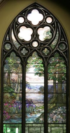 an ornate stained glass window with flowers and trees in the background, inside a church