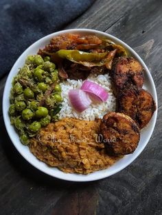 a white bowl filled with rice, meat and vegetables on top of a wooden table