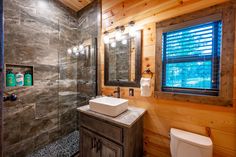 a bathroom with a sink, toilet and shower in the corner next to a window