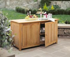 an outdoor table with food and drinks on it in front of a stone patio area