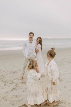 a family standing on the beach holding hands