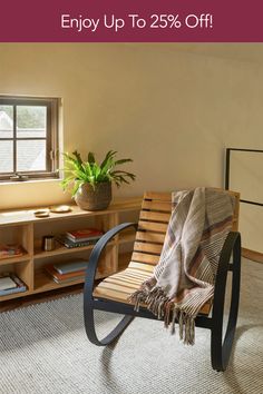 a chair with a blanket on it in front of a window and bookshelf