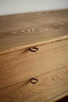 a close up of a wooden dresser with rings on the drawer knobs and handles