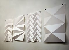 three pieces of paper are hanging on the wall next to each other with different shapes