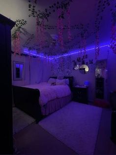 a bed room with a neatly made bed and purple lights hanging from the ceiling above it