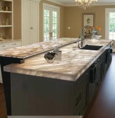 a large kitchen island with two sinks in the center and cabinets on both sides behind it