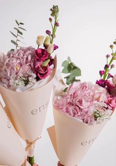 two bouquets of flowers are wrapped in pink paper