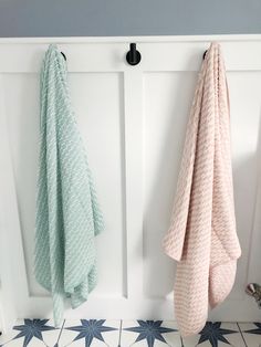 two towels are hanging on the wall next to a coat rack and door knobs