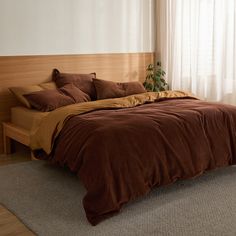 the bed is made with brown sheets and pillows