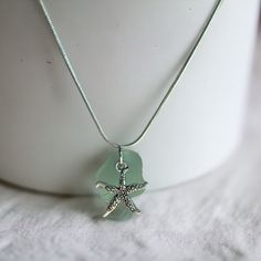 a green sea glass necklace with a starfish charm hanging from it's side