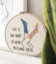 a hand embroidered hoop hanging on a window sill that says life is too short to wear matching socks