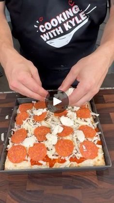 a person in an apron is cutting up some pizza on a pan with a spatula