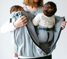 a woman is holding a baby in a sling that's attached to her back