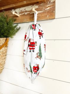 a santa clause bag hanging on the wall next to a basket with pine branches in it